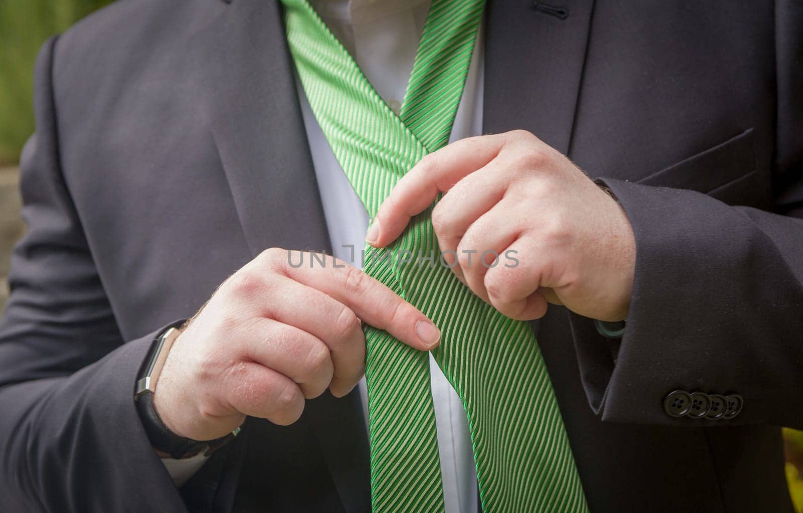 Man putting his tie on getting ready for his event