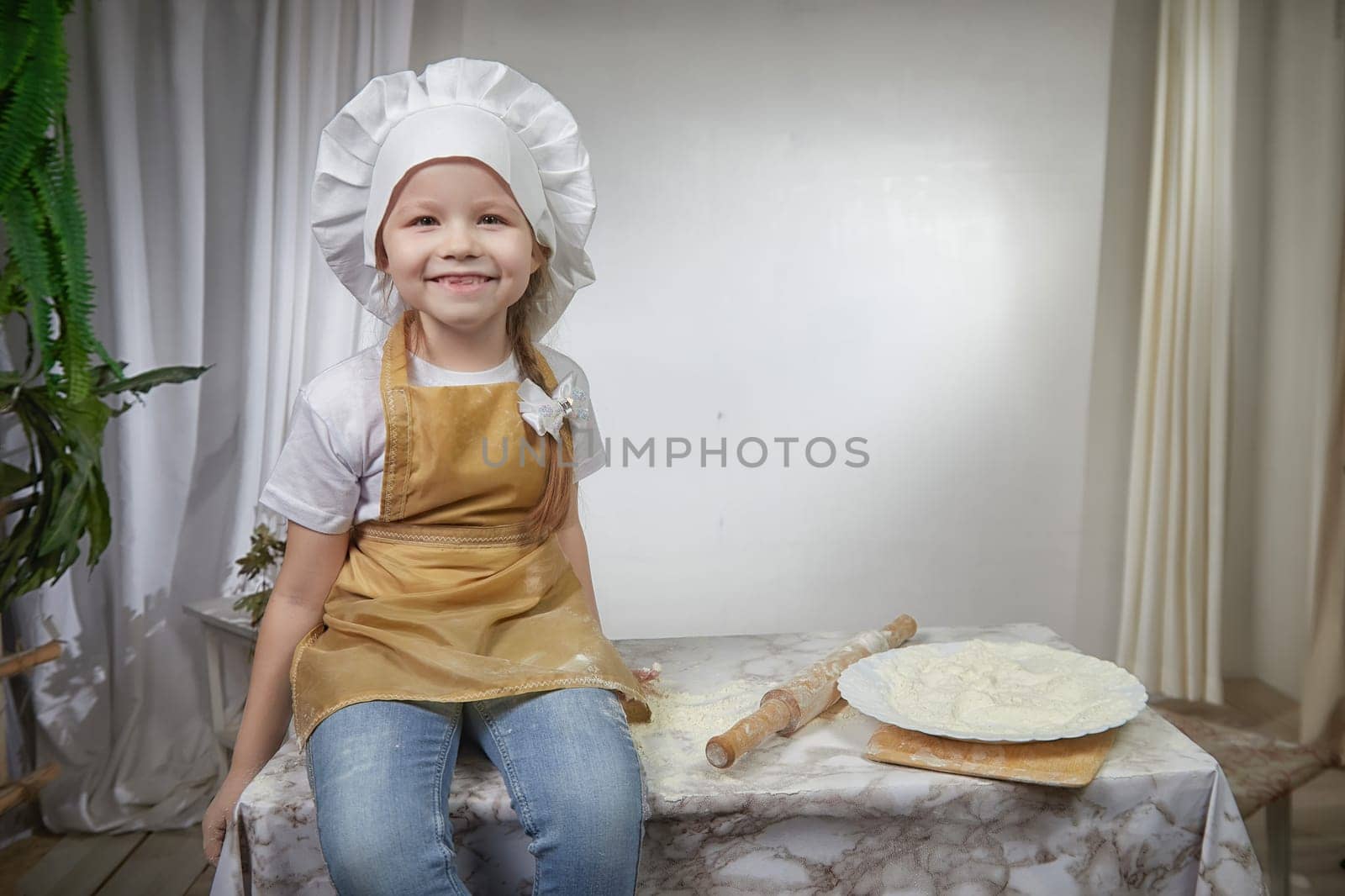 Cute oriental girl cooking in the kitchen on Ramadan, Kurban-Bairam, Eid al-Adha. Funny female child at cook photo shoot. Pancakes, Maslenitsa, Easter