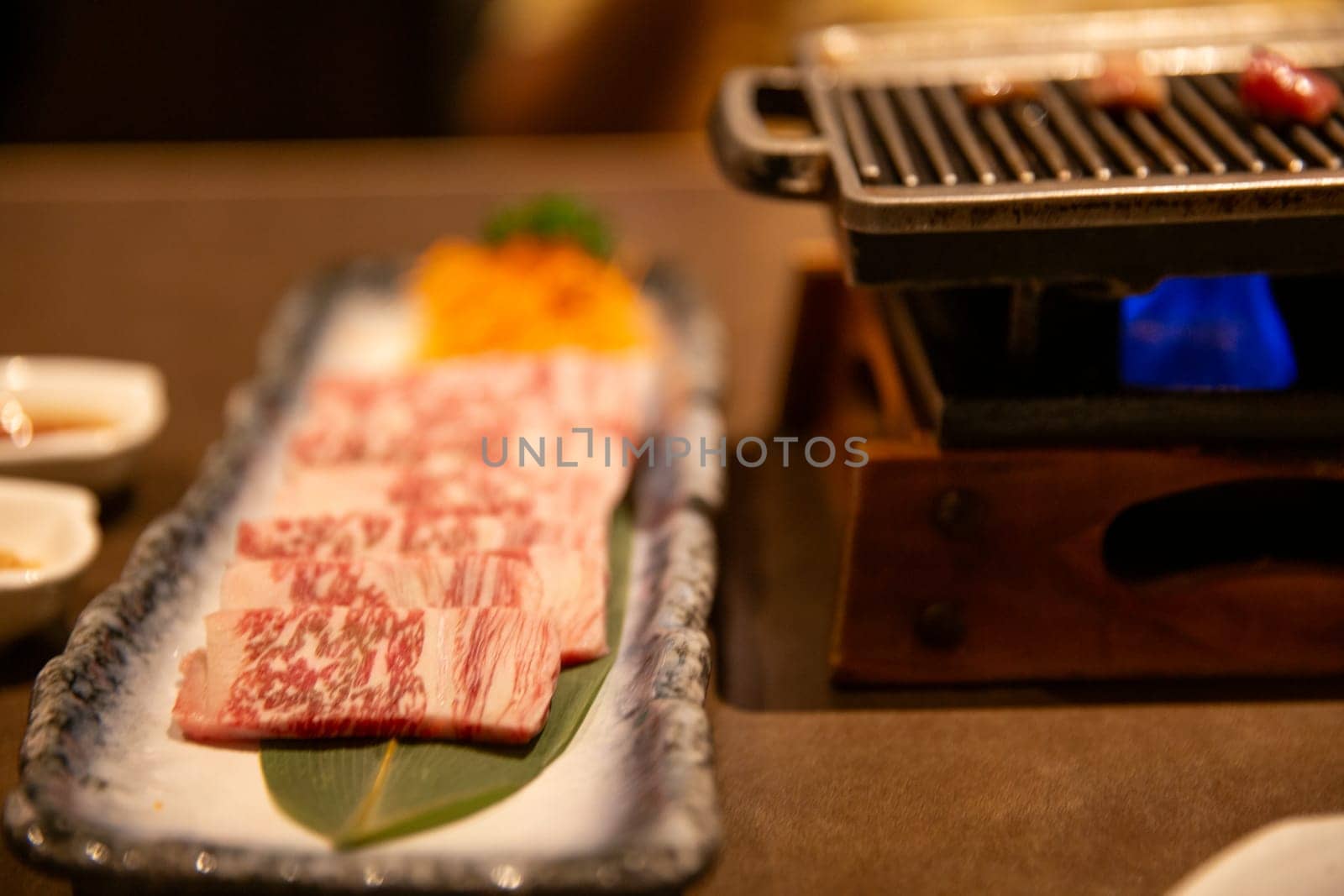 Raw wagyu beef next to a grill
