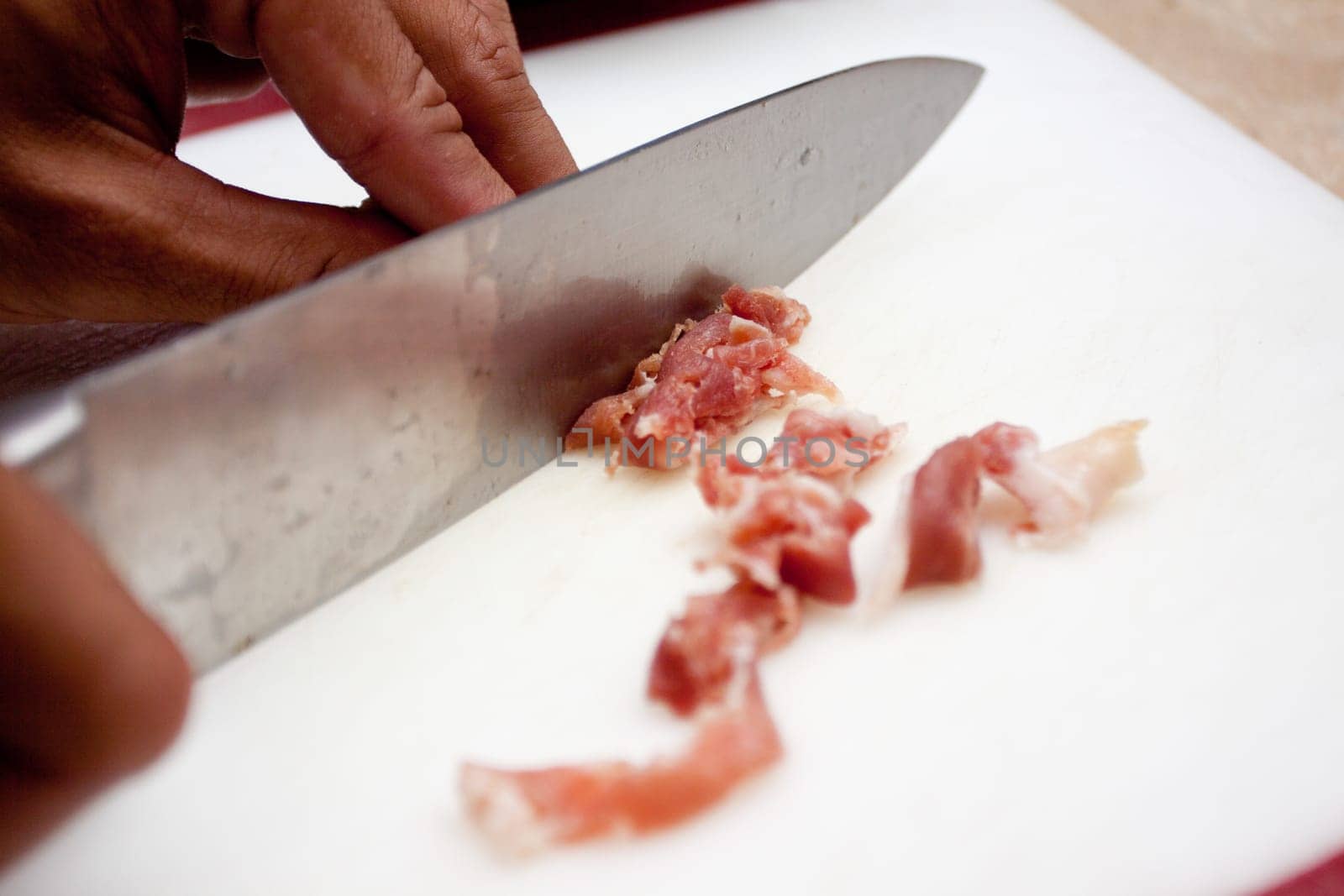 slicing up procuitto with a knife to used as a topping