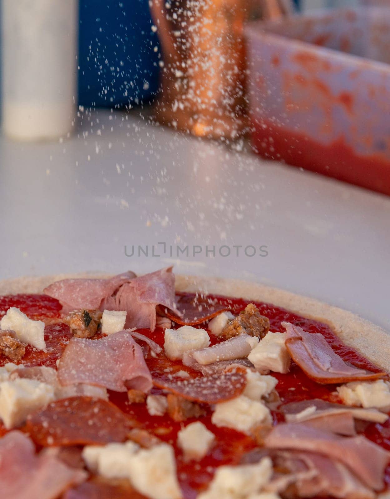 Sprinkling grated parmasan over a pizza