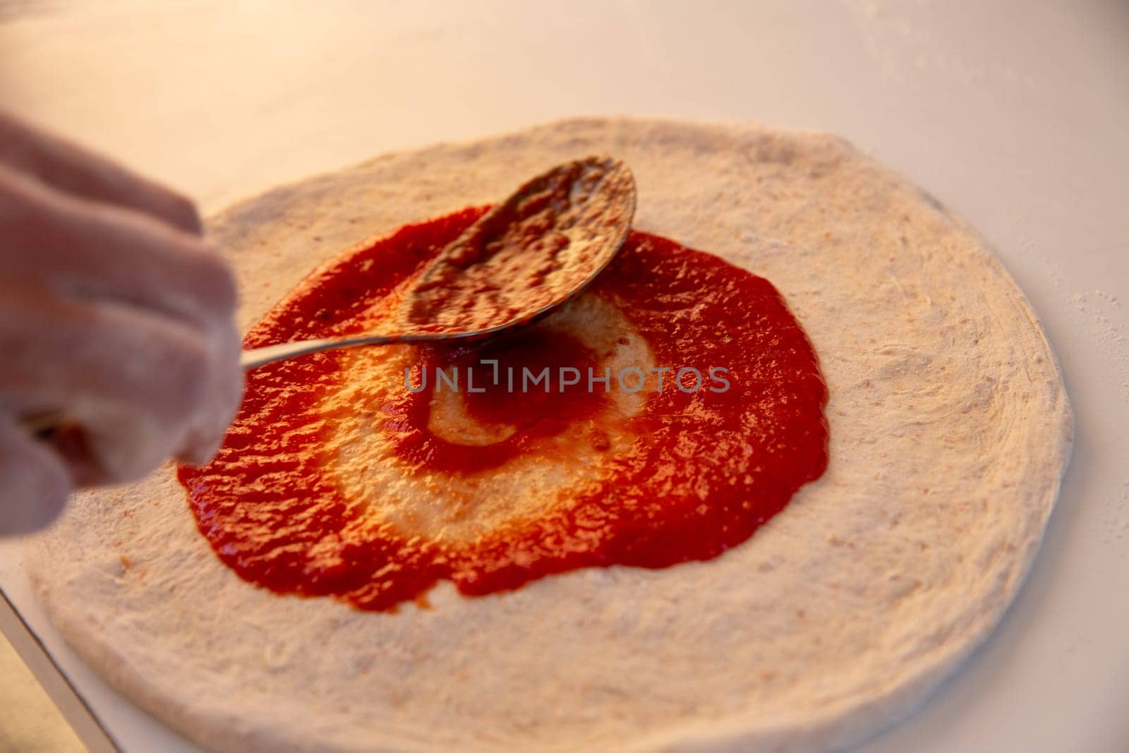 Spreading Marinara on a Pizza before adding cheese