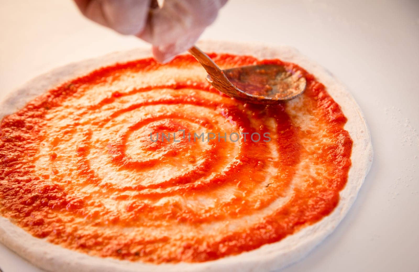 Spreading Marinara on a Pizza before adding cheese