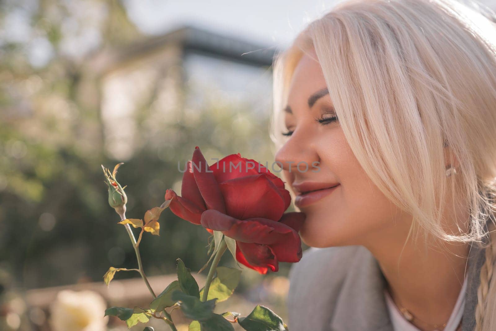 A woman is smelling a red rose. Concept of happiness and contentment, as the woman is enjoying the scent of the flower