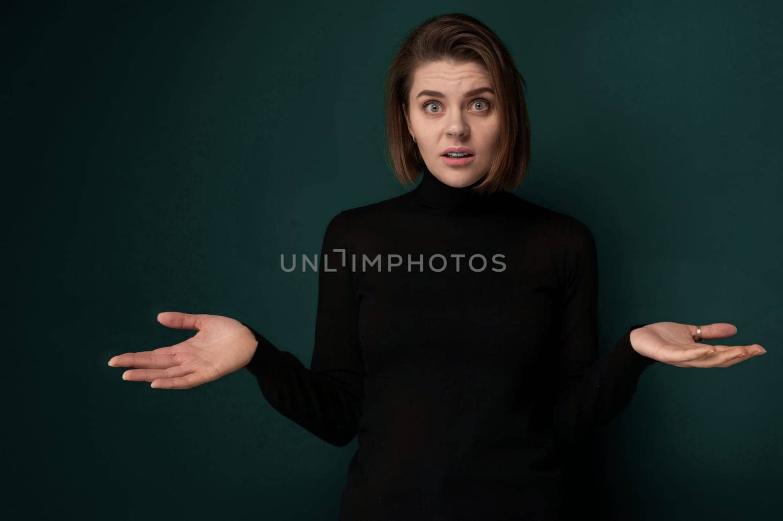 A woman dressed in a black shirt is extending her hands outward. Both of her hands are open, palms facing upward. She appears to be standing with a neutral expression, looking directly ahead.