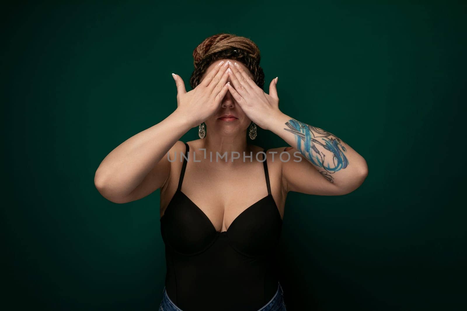 A woman sitting with her hands covering her eyes in a gesture of blocking out light or shielding herself from a bright or overwhelming situation. She appears to be seeking privacy or taking a moment to collect her thoughts.