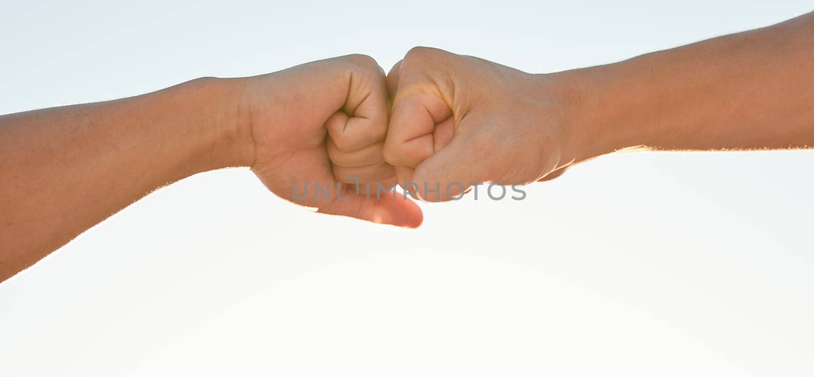 Fist bump, sky and hands of people for support, agreement and collaboration outdoors. Friends, teamwork and closeup of greeting gesture for friendship, community and solidarity on sky background.