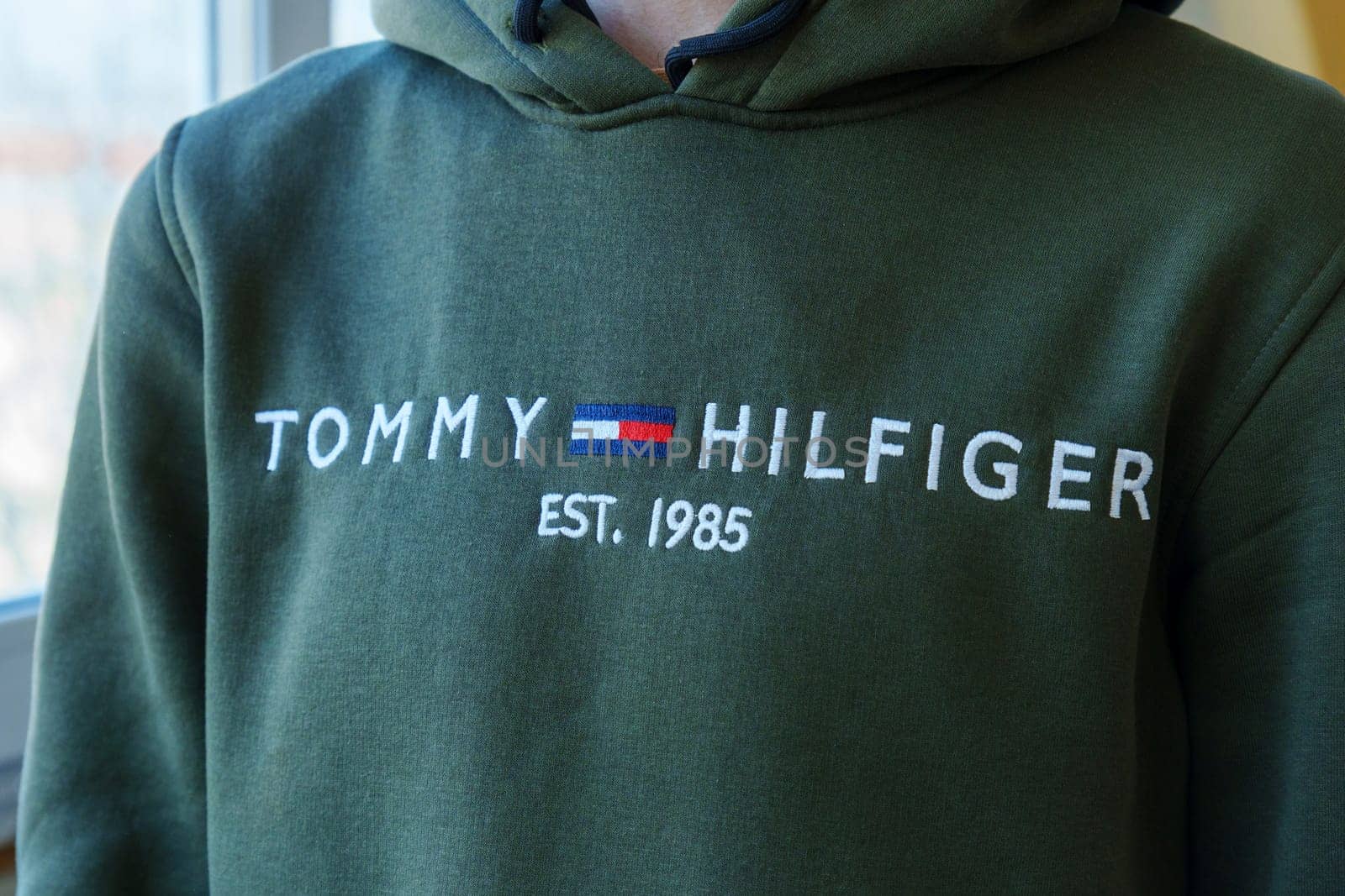 Tyumen, Russia-January 11, 2024: Person in Green Tommy Hilfiger Sweatshirt close up logo. Selective focus