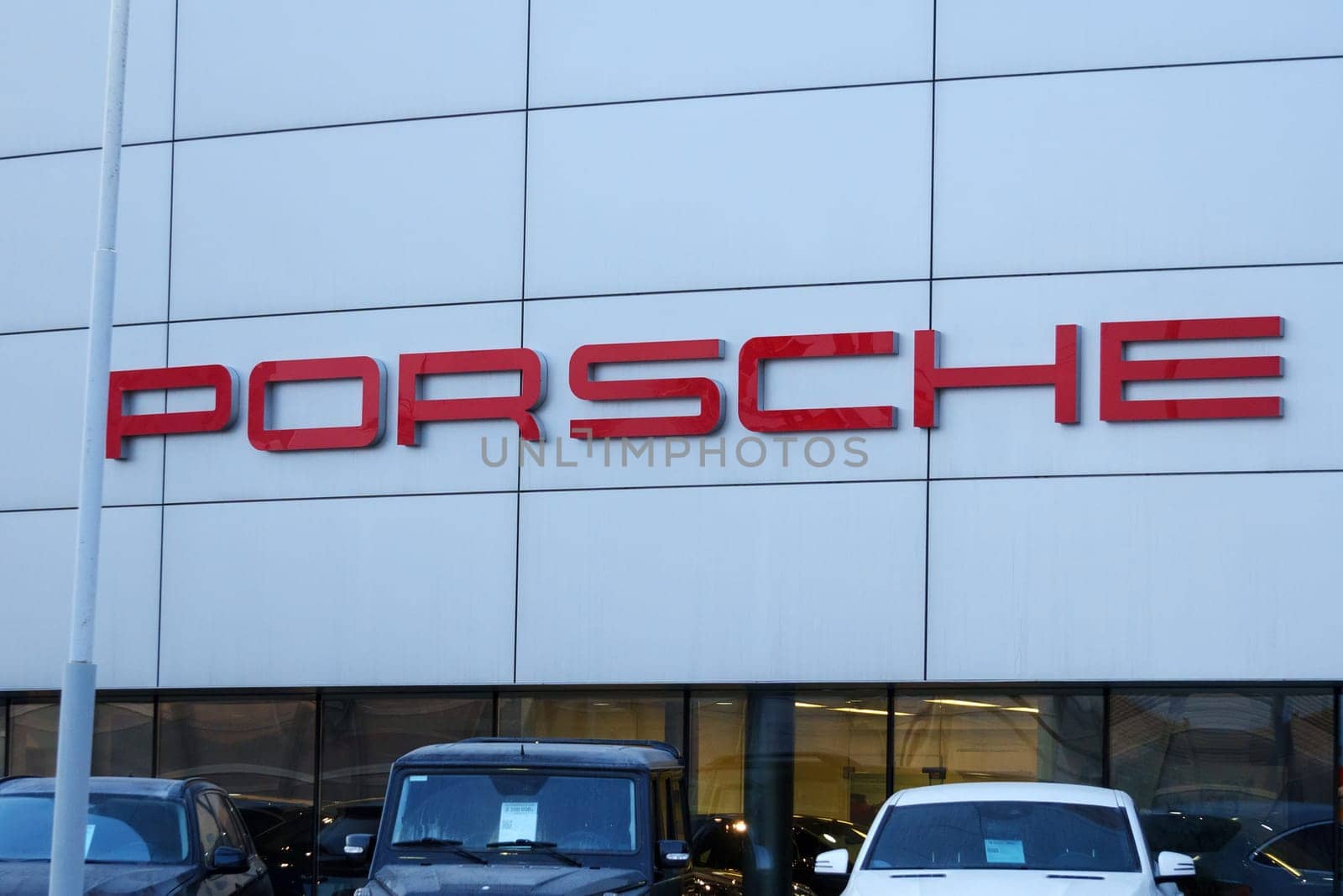 Tyumen, Russia-March 18, 2024: Vehicles parked outside a Porsche dealership, showcasing luxury cars and the iconic Porsche logo.