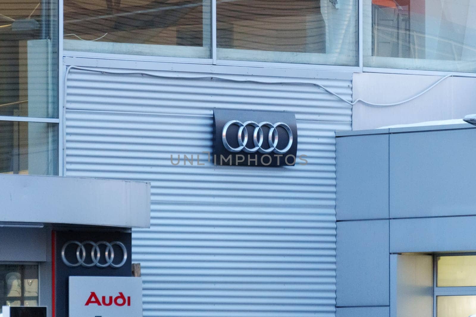 Tyumen, Russia-March 18, 2024: Audi logo are mounted prominently on a textured gray wall against a clear sky by darksoul72