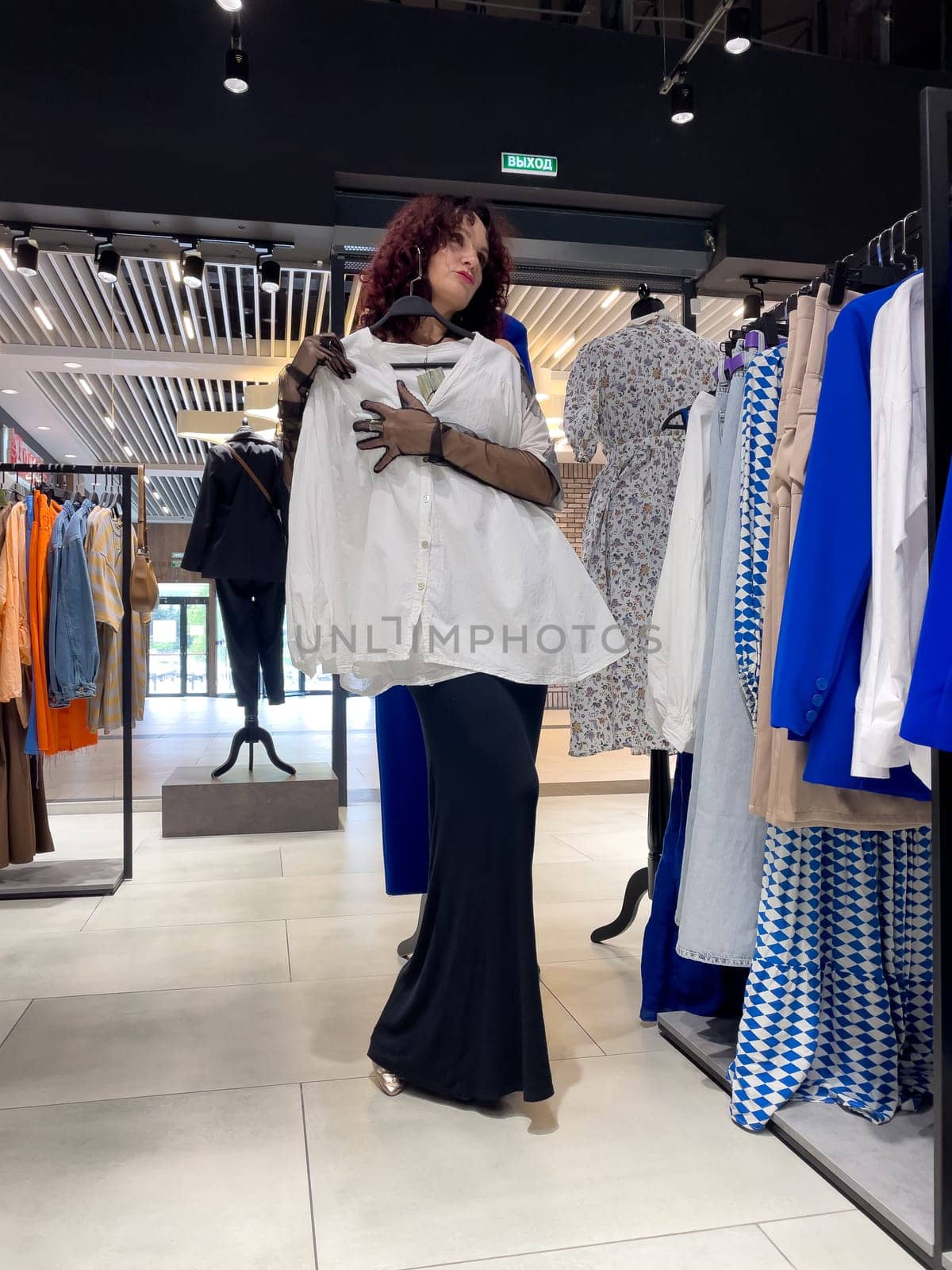 Shopping woman, women's fashion clothes in a store, boutique. Woman choosing clothes in a store by Matiunina