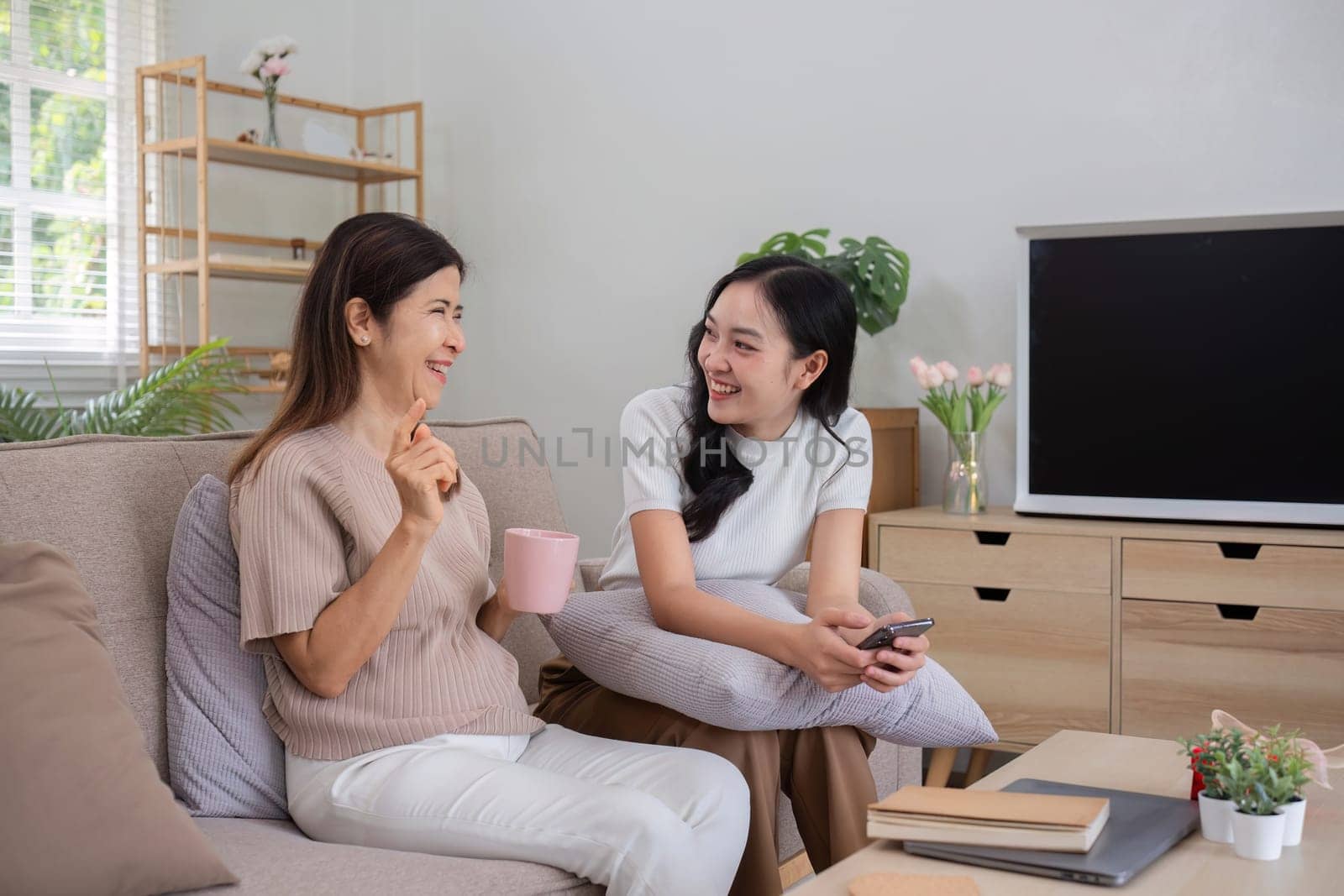 Mother and teenage daughter sitting together in the living room on vacation..