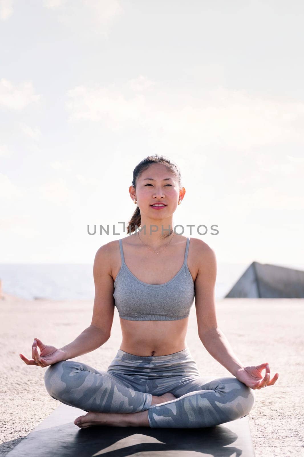woman doing yoga meditation sitting by the sea by raulmelldo