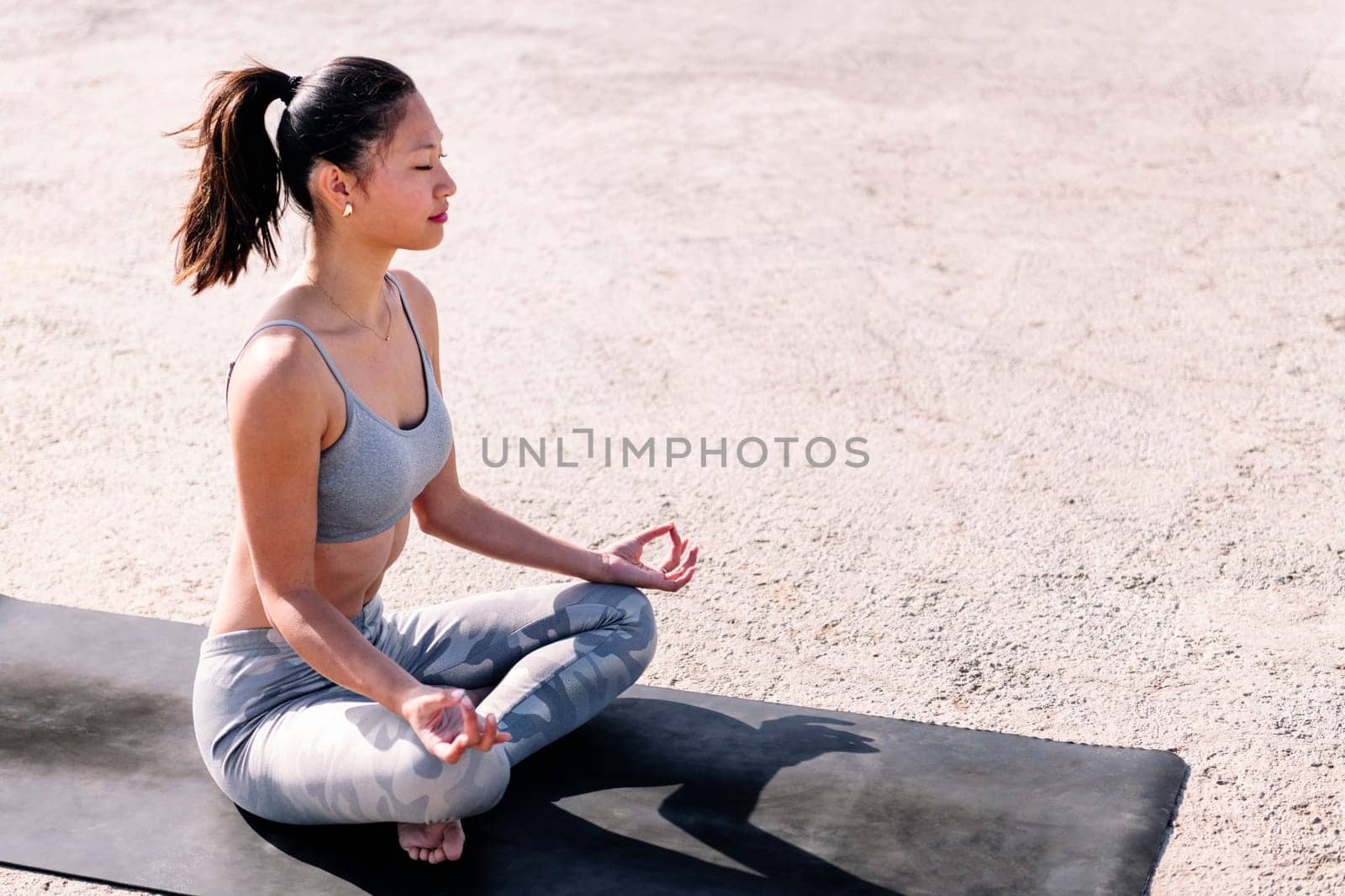 young asian woman doing meditation on a yoga mat by raulmelldo