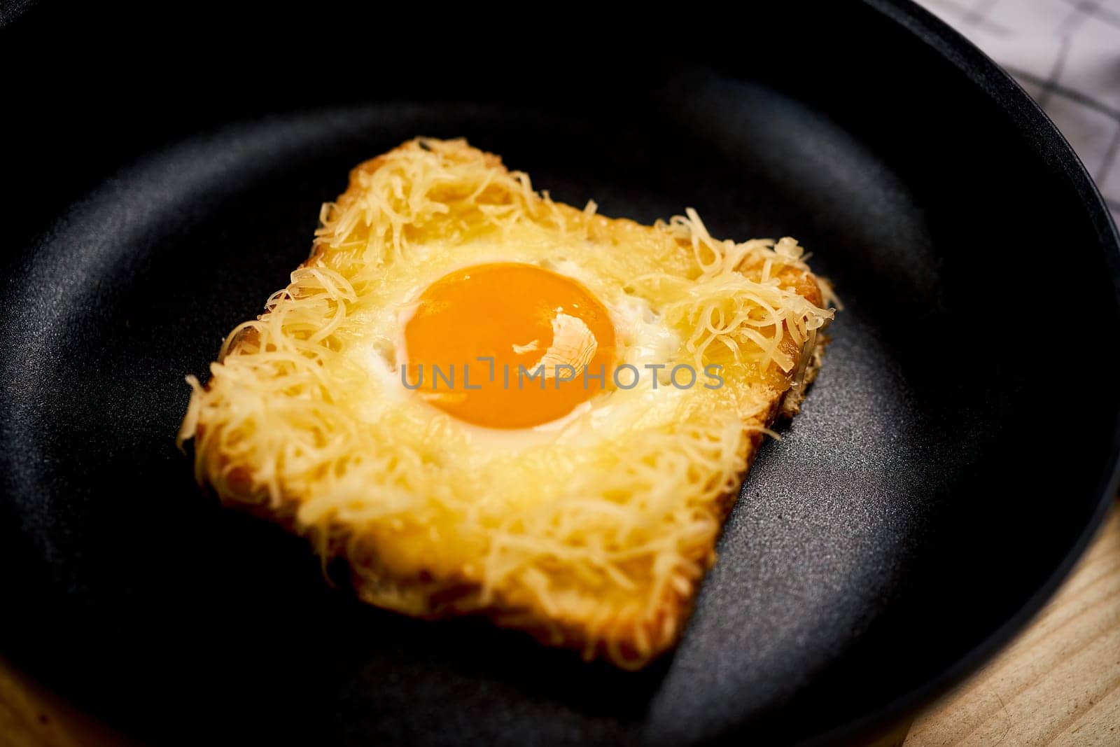 Delicious toast with fried egg in pan on wooden kitchen table by superstellar