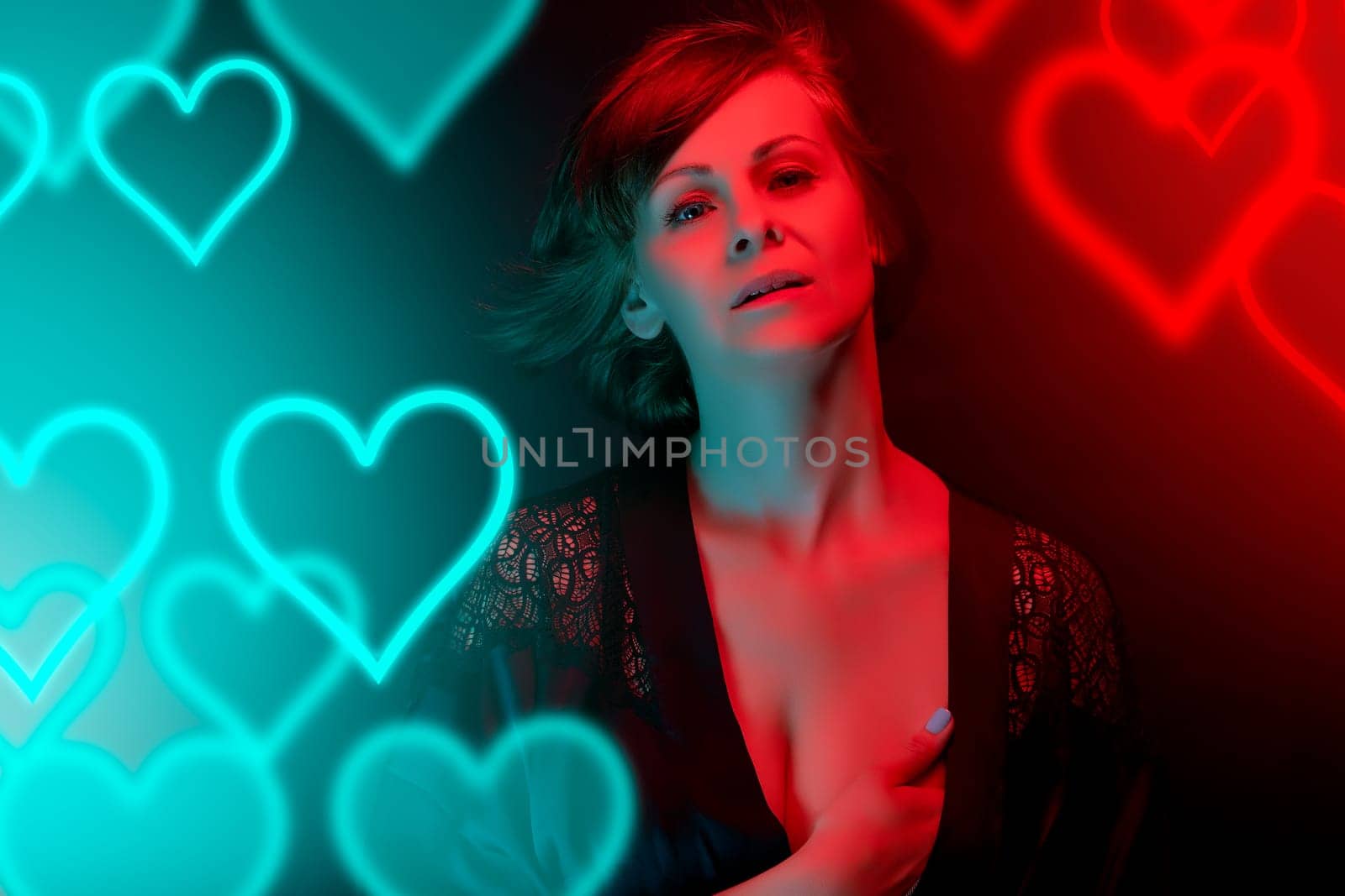 Beautiful attractive young woman posing in satin bathrobe in neon light in the studio.