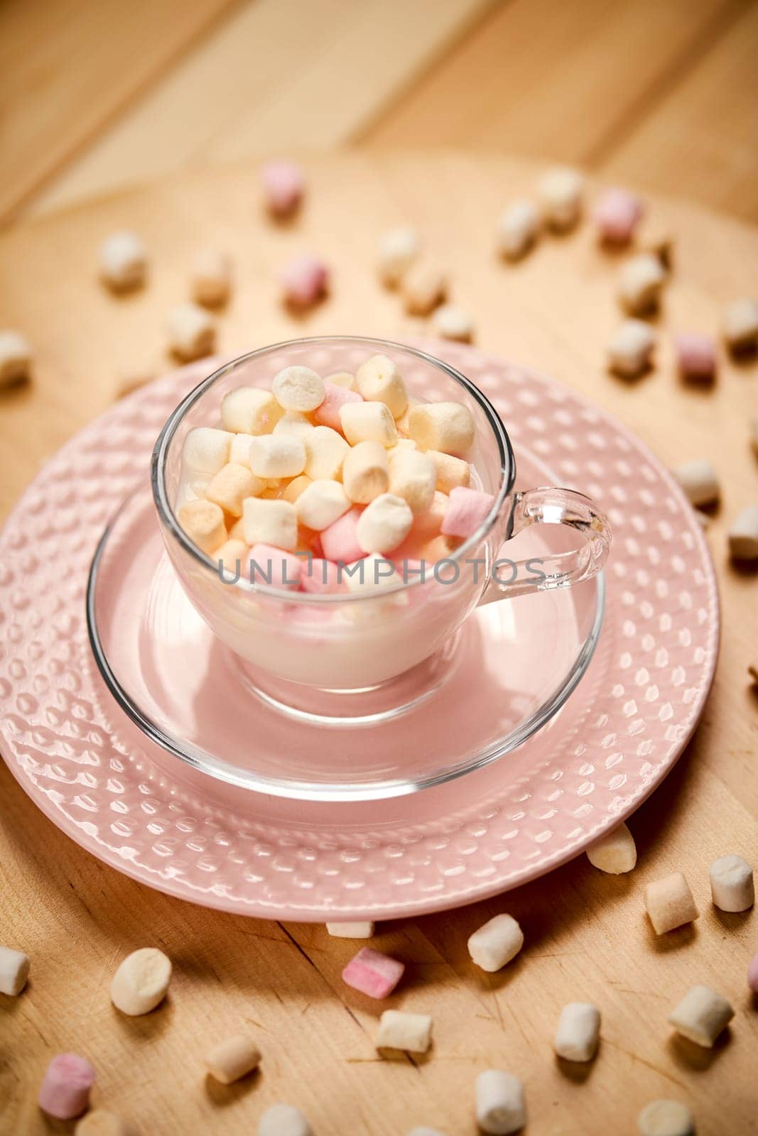Cup with hot milk and colorful marshmallows on wooden table by superstellar