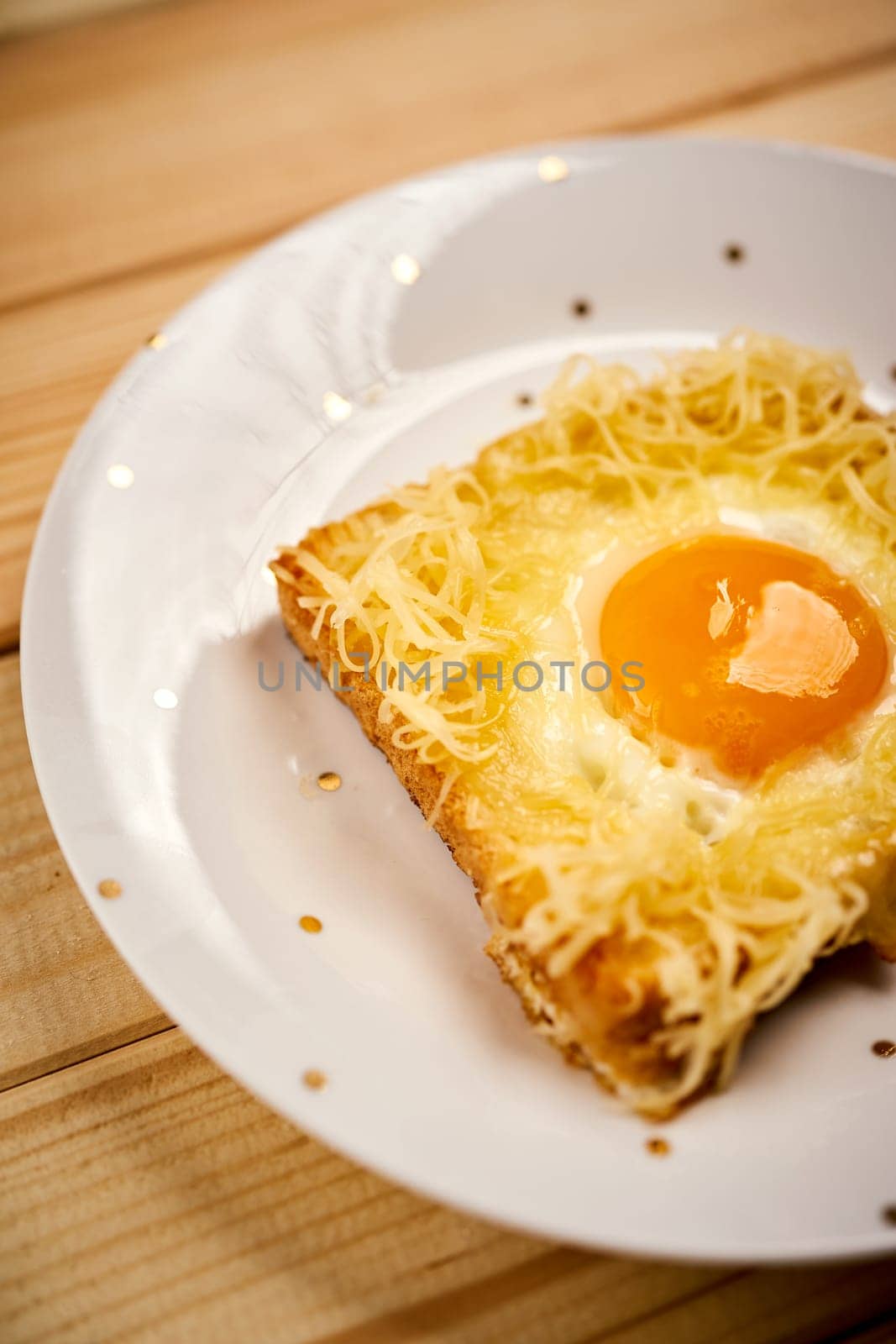 Delicious toast with fried egg on plate on bright wooden kitchen table