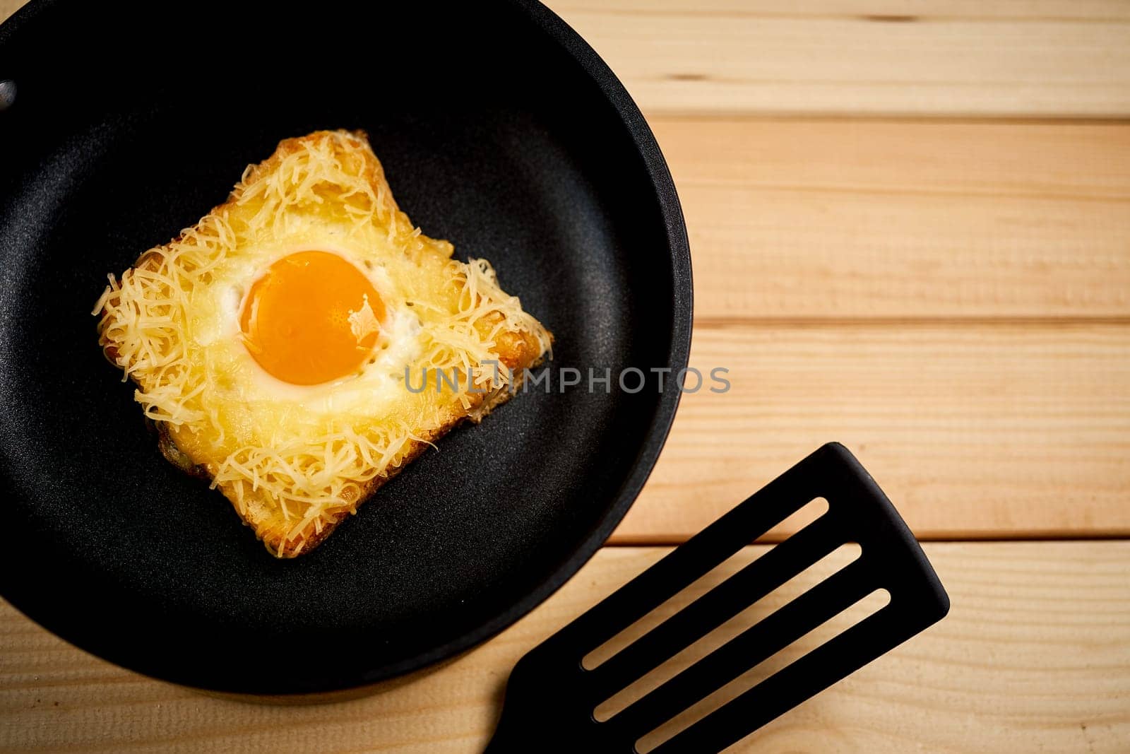 Delicious toast with fried egg and cheese in pan on wooden kitchen table