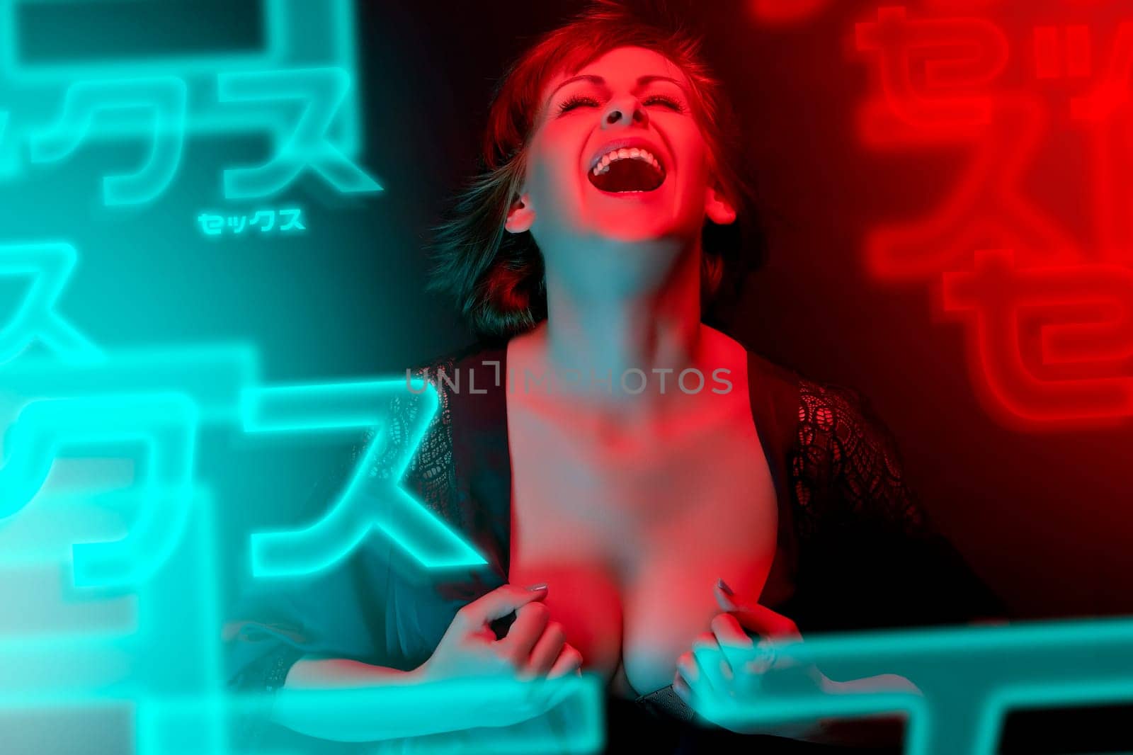 Beautiful attractive young woman posing in satin bathrobe in neon light in the studio.