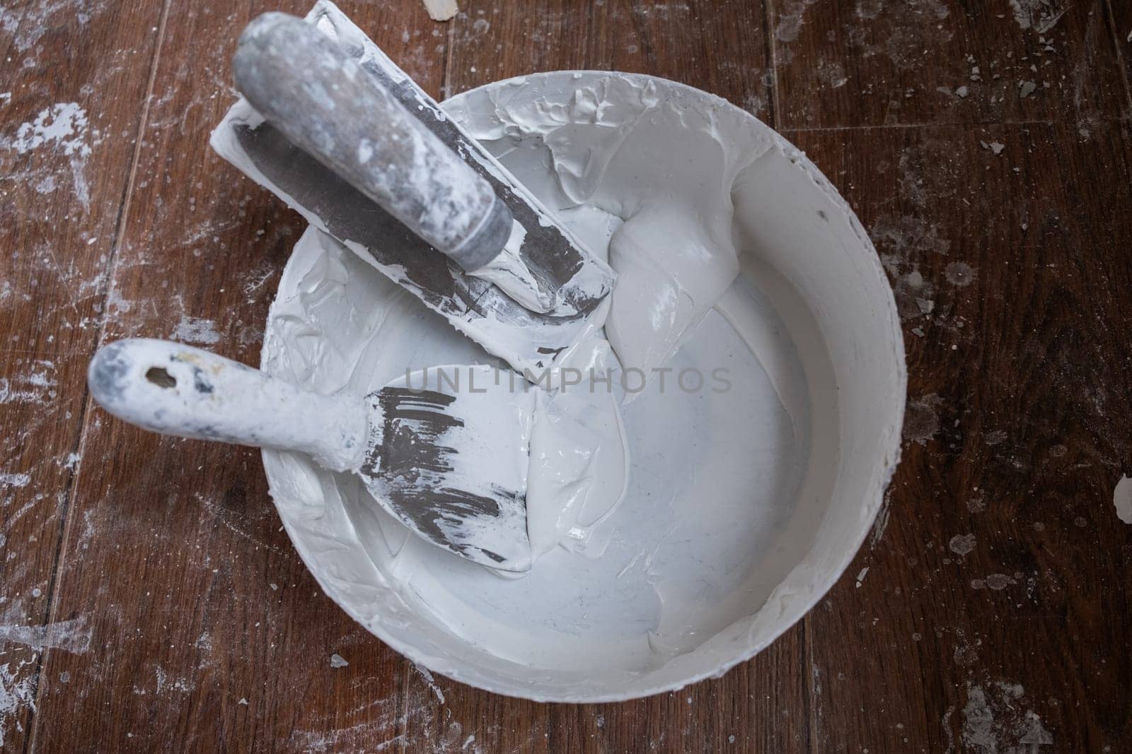 Applying decorative putty. White abstract texture of surface covered with putty. textured background of filler paste applied with putty knife in irregular dashes and strokes. Rough surface plaster