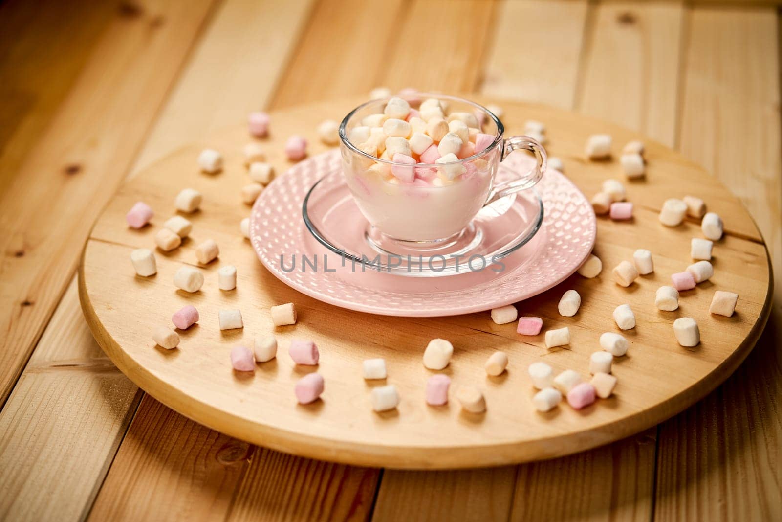 Cup with hot milk and colorful marshmallows on wooden table by superstellar