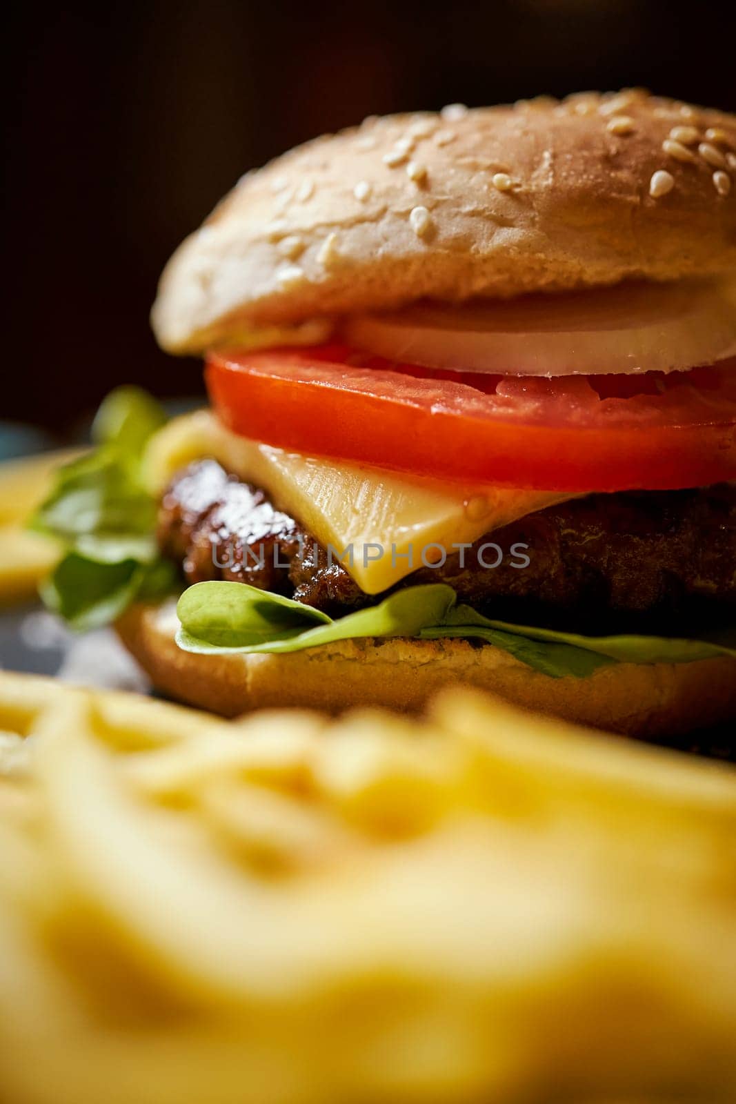 delicious cheeseburger surrounded by french fries on a black table