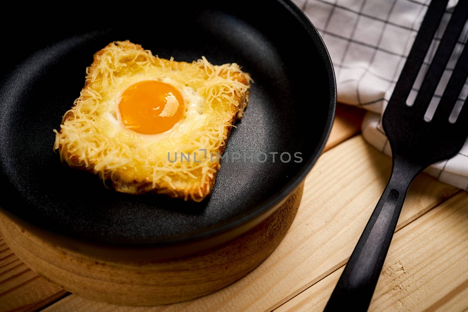 Delicious toast with fried egg and cheese in pan on wooden kitchen table