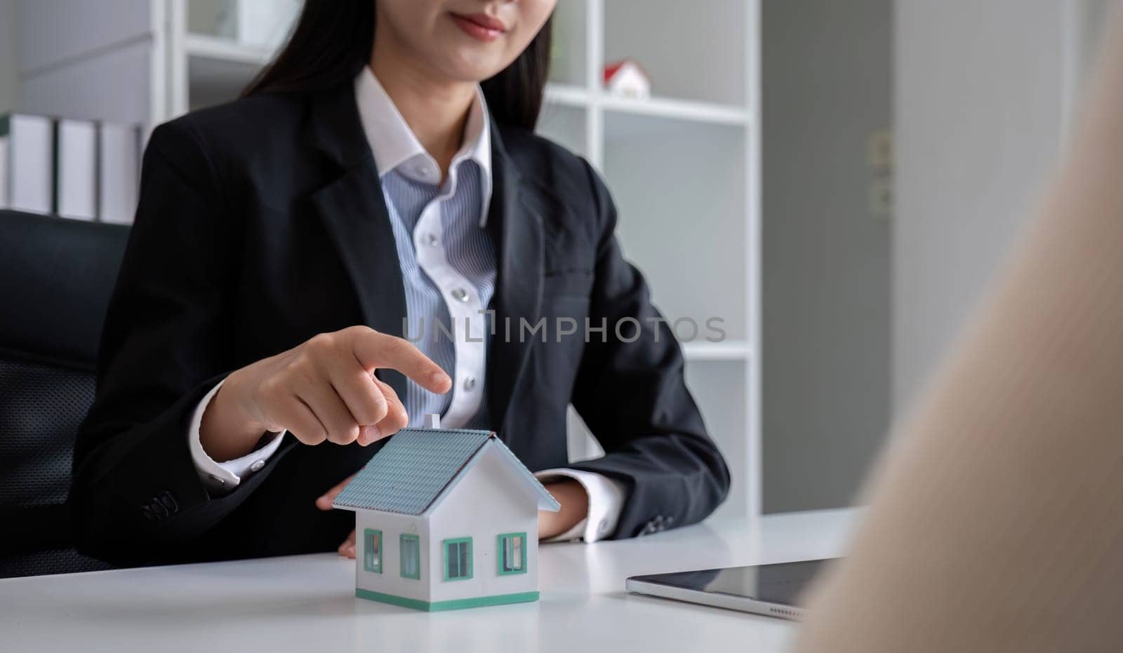 A real estate agent or insurance agent presents a house plan and insurance contract to an Asian couple..