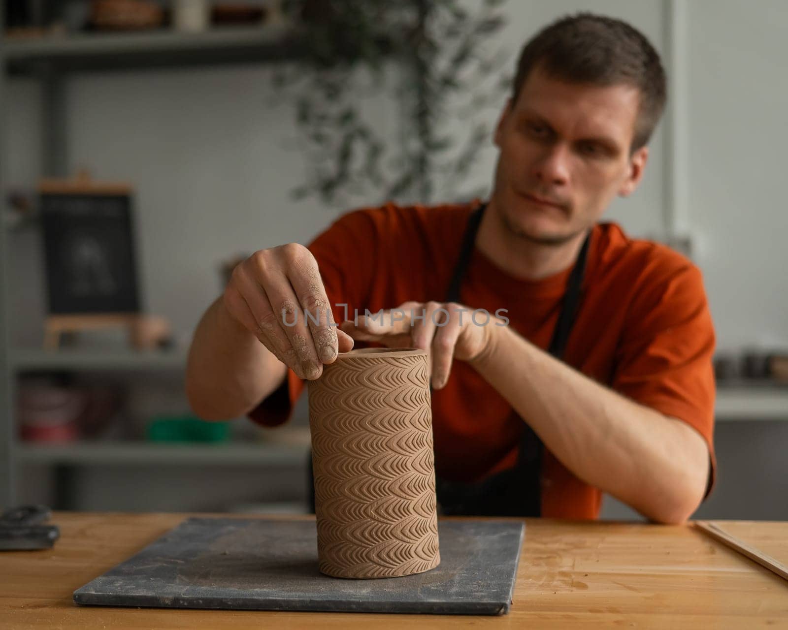 Potter sculpts a patterned cylinder from clay. by mrwed54