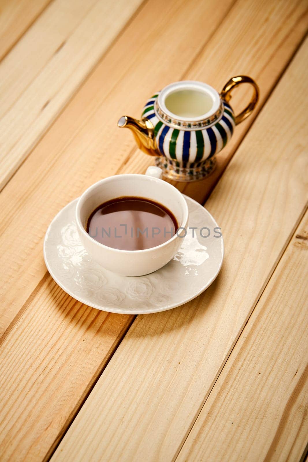 One small cup with aromatic coffee with milk on wooden bright table