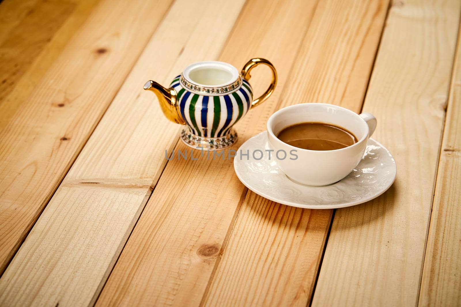 One small cup with aromatic coffee with milk on wooden bright table