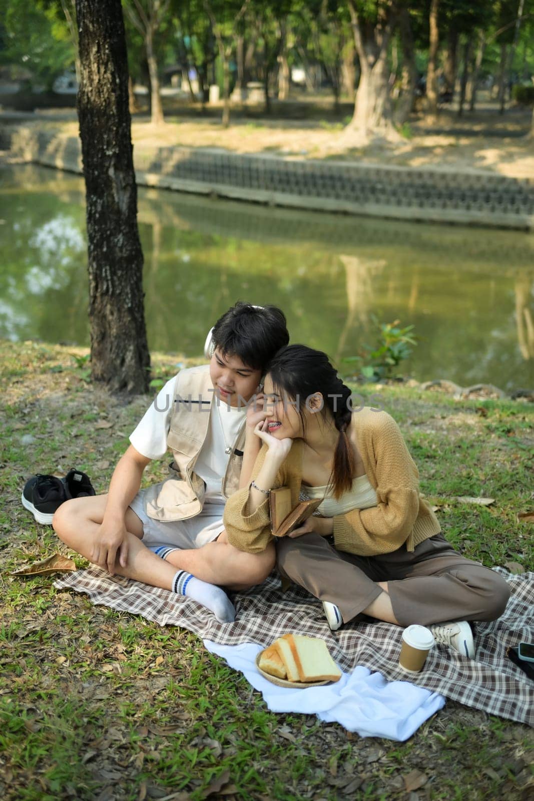 Happy young couple having picnic on a sunny day, spending time together at park.