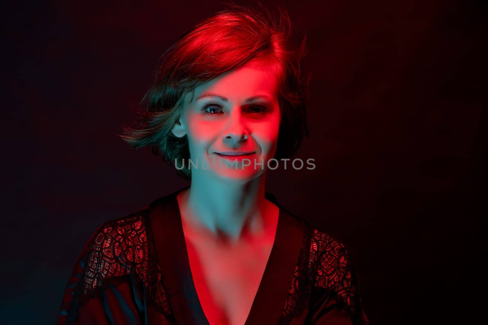 Beautiful attractive woman posing in satin bathrobe in neon light. by superstellar