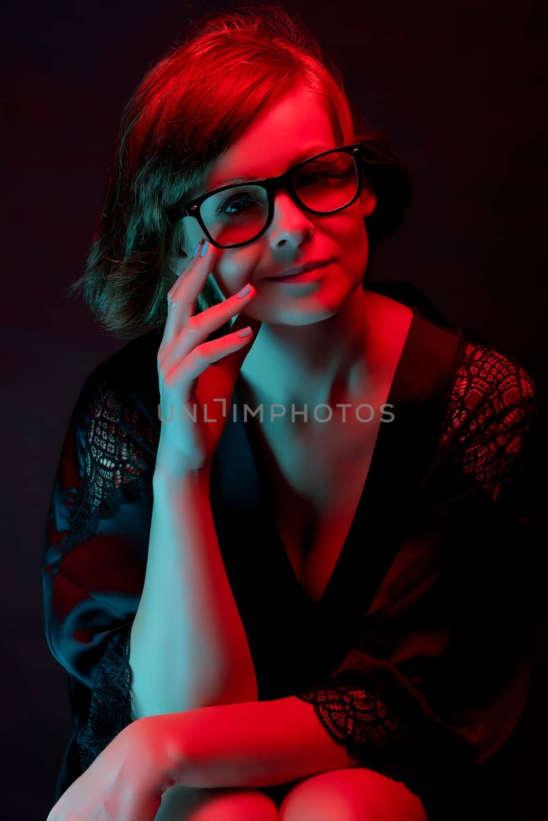 Beautiful attractive woman in glasses in satin bathrobe in neon light by superstellar