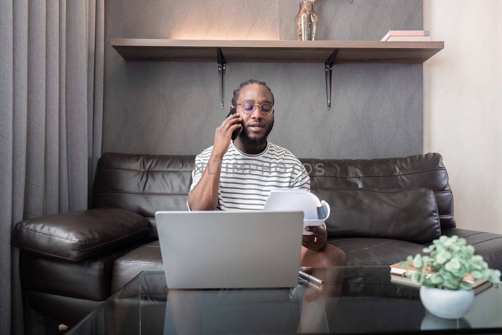 Professional man working remote from home with technology. African American male has a business meeting on an audio call phone by nateemee