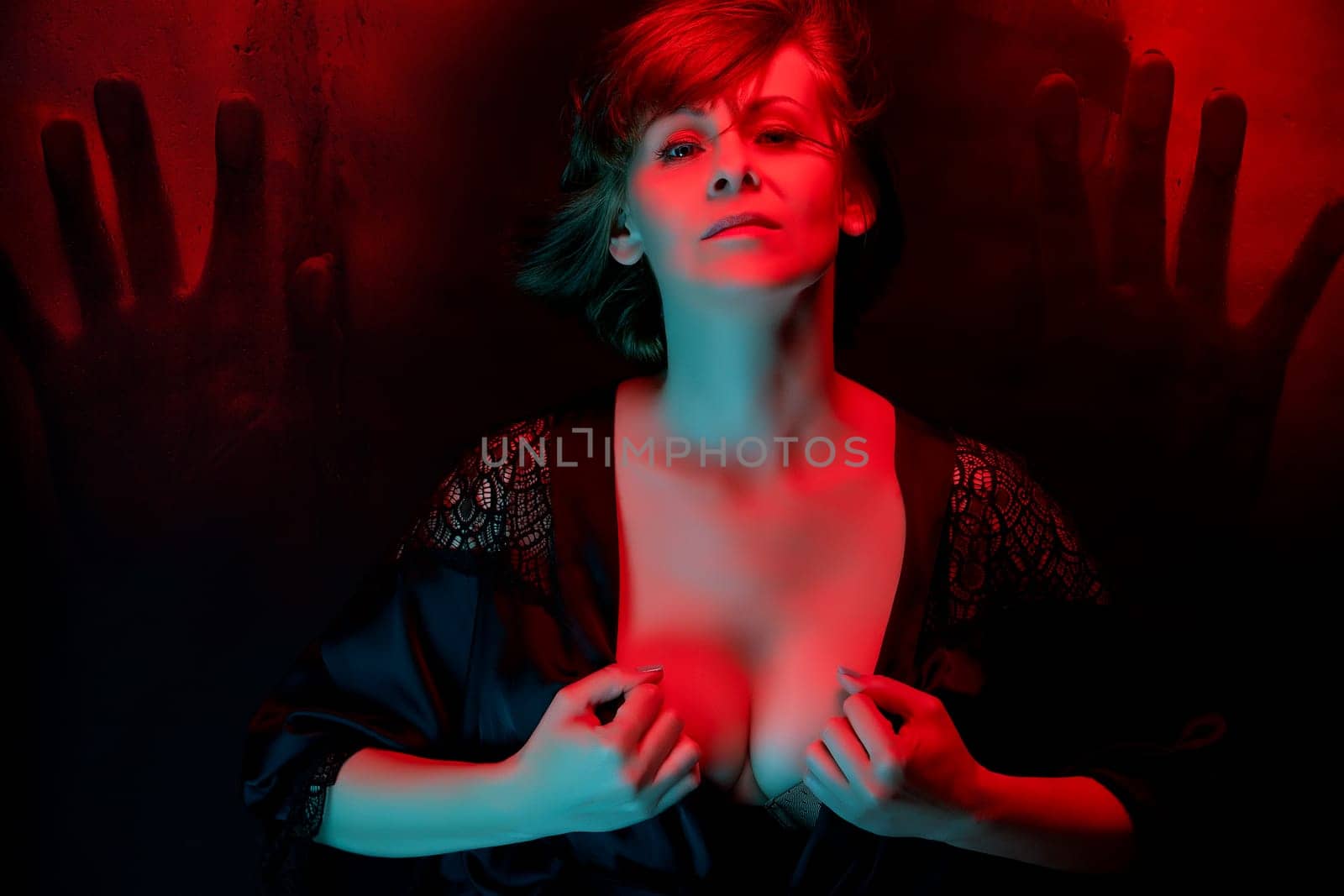 Beautiful attractive young woman posing in satin bathrobe in neon light in the studio.