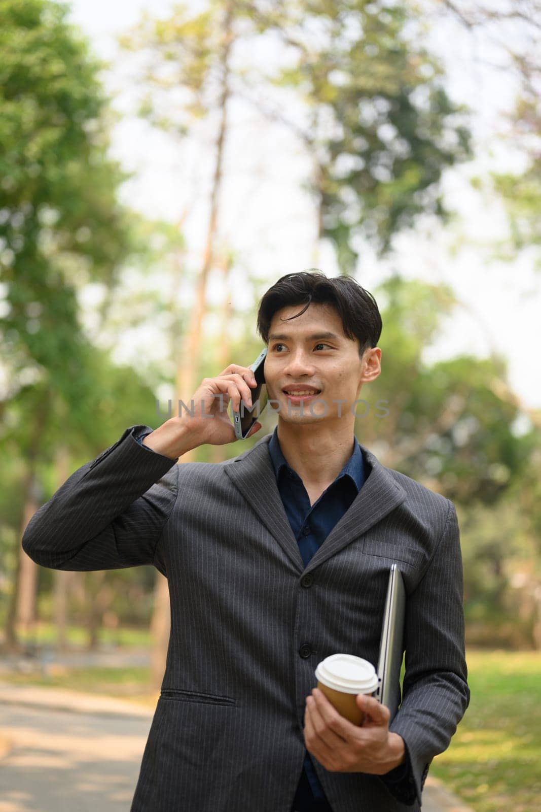 Portrait of handsome businessman having pleased cell phone conversation at outdoor by prathanchorruangsak