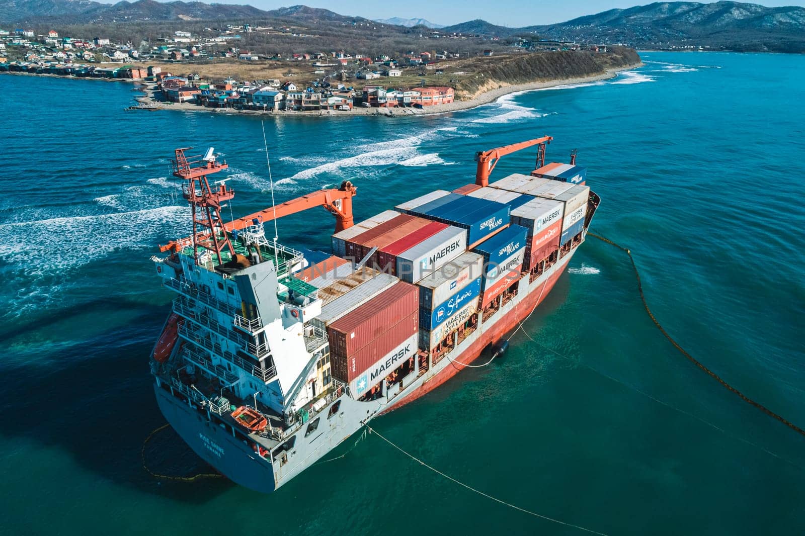 Aerial view of a RISE SHINE container cargo ship stands aground after a storm with floating boom around the ship to prevent the spread of petroleum. Container ship ran aground during the storm.