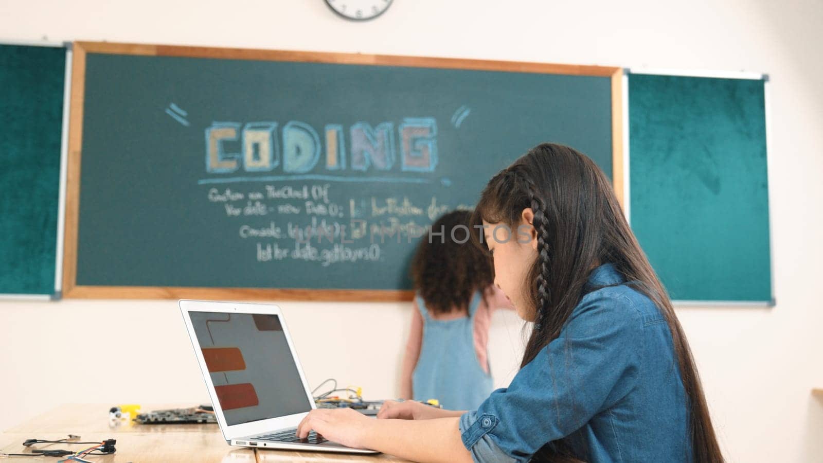 Girl writing engineering prompt by using AI software or programing system to generate AI on table with electronic main board at stem class while student writing software development plan. Pedagogy.