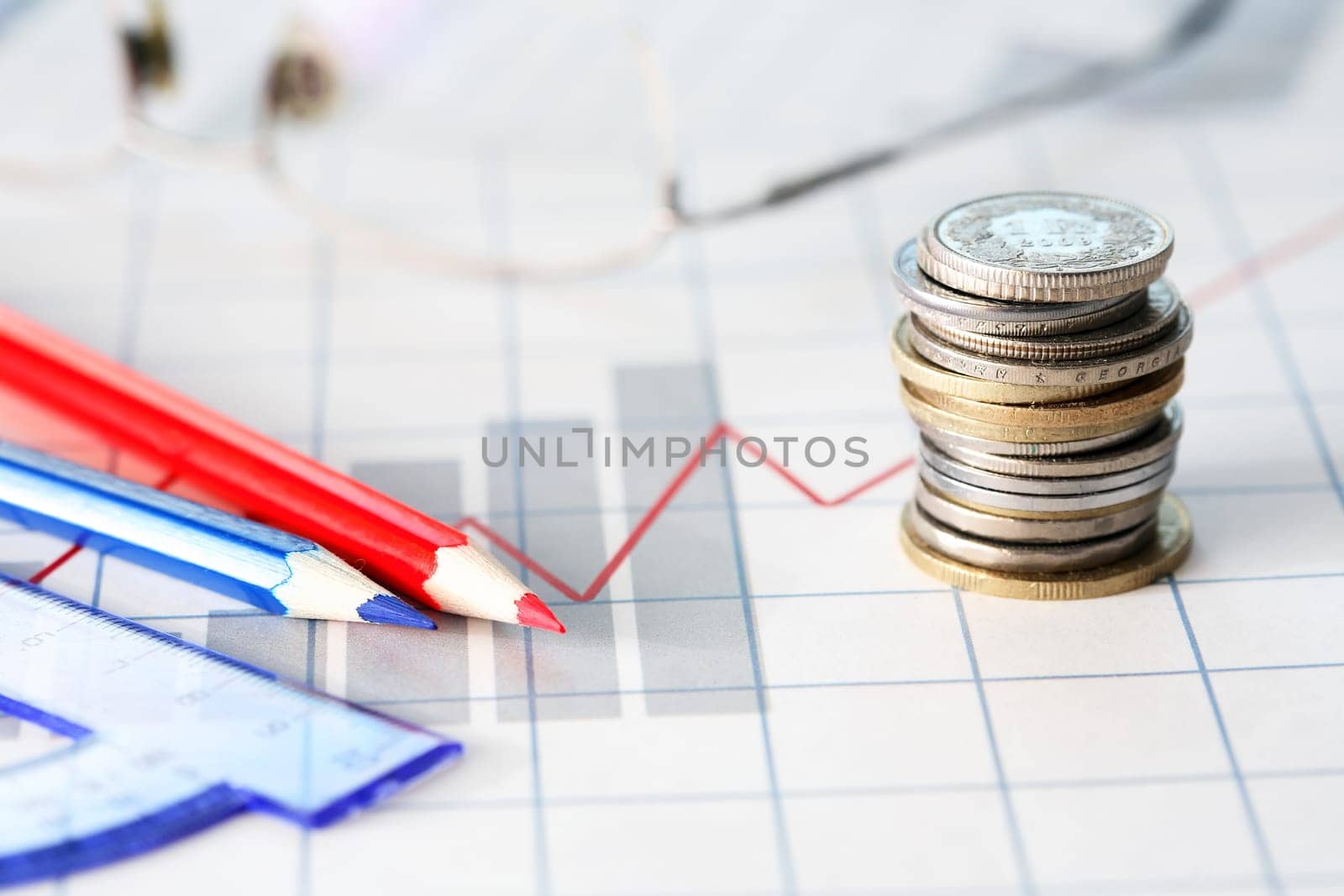 Business concept. Set of drawing tools with coins on diagram background