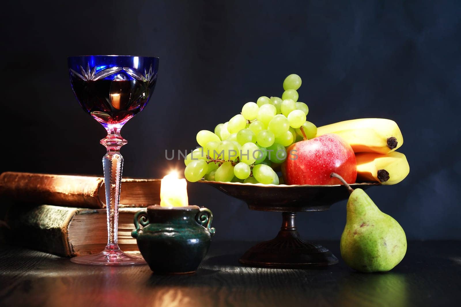 Nice vintage still life with wine glass near candle and fruits