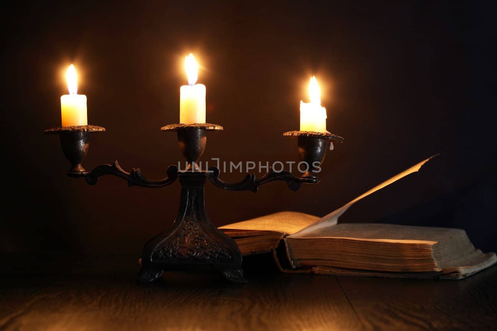 Nice vintage candlestick with lighting candle near old book