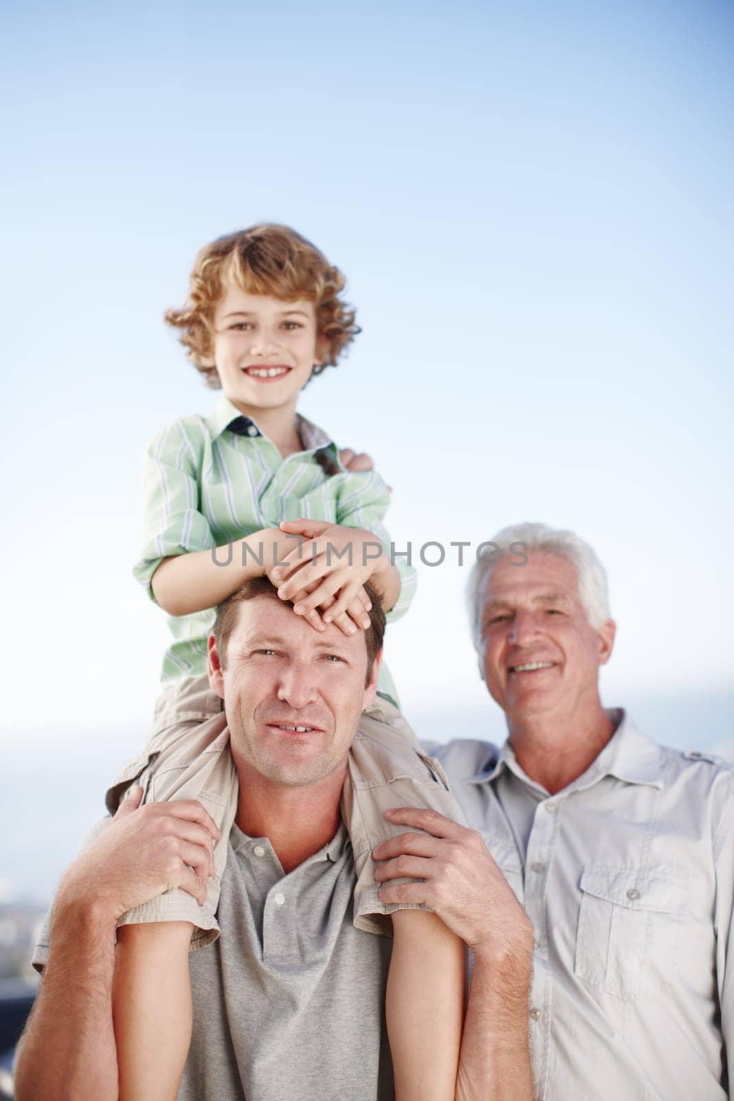 Portrait of grandfather, father and child by ocean and blue sky for bonding, relationship and relax together. Family, fun and grandpa, dad and young boy on shoulders for holiday, vacation and weekend by YuriArcurs