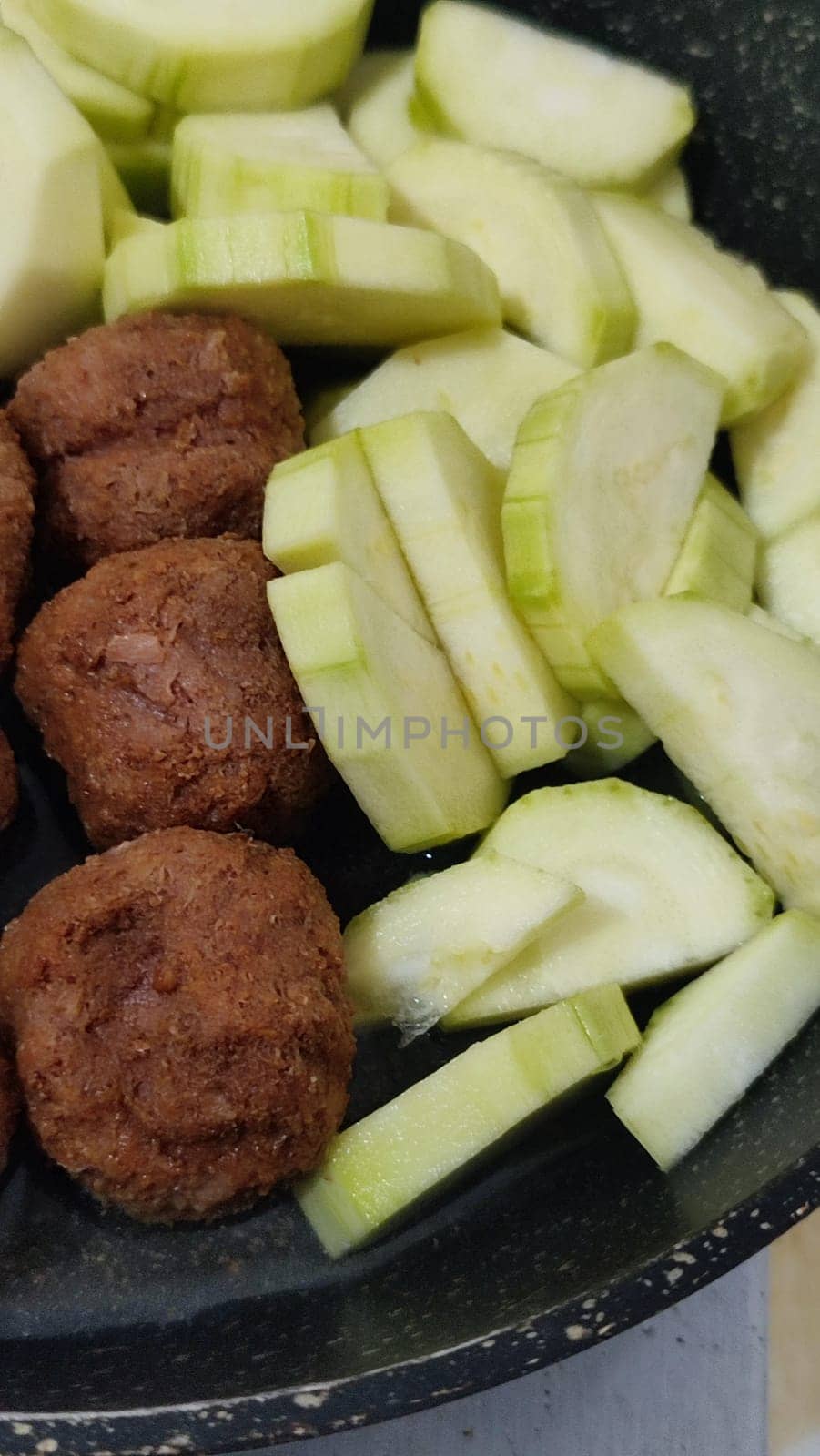 green zucchini and cutlets meatballs in a frying pan, homemade food, cooking. High quality photo