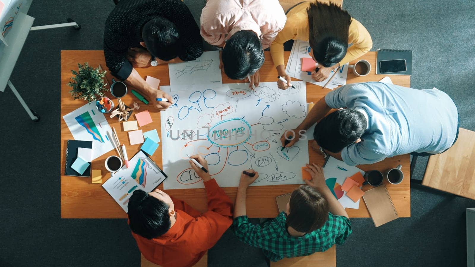 Group of business people writing and making mind map to brainstorming marketing idea at meeting. Top aerial view of investors sharing plan or strategy by using sticky notes. Top view. Convocation.