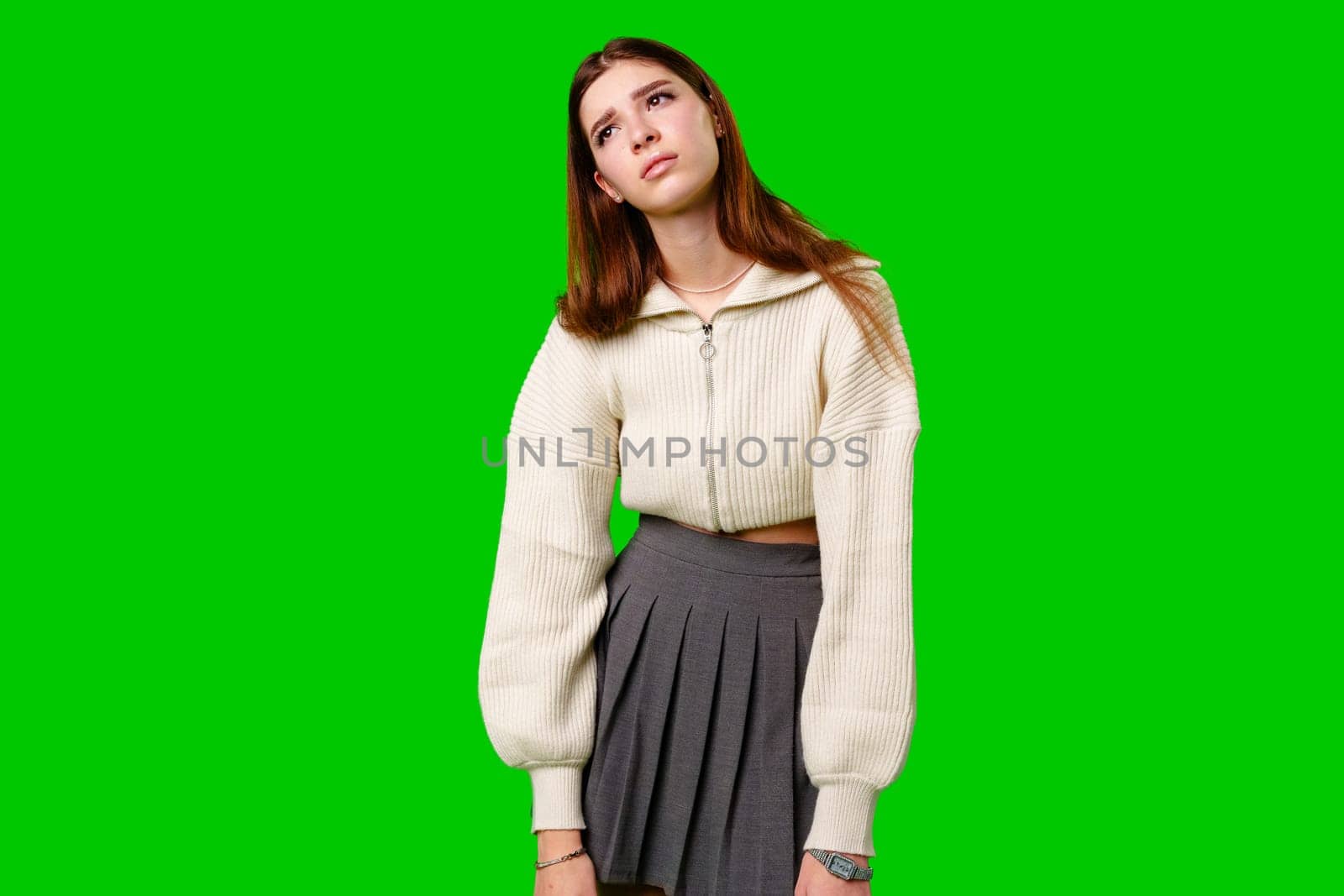 A woman wearing a skirt and sweater stands confidently against a vibrant green background. Her posture exudes strength and poise as she gazes ahead.