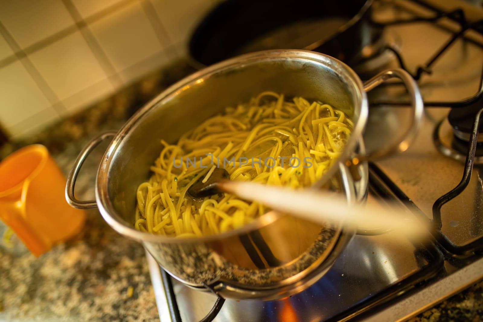 Steam rises from a pot of boiling pasta on the stove, capturing the simple yet essential process of pasta preparation.