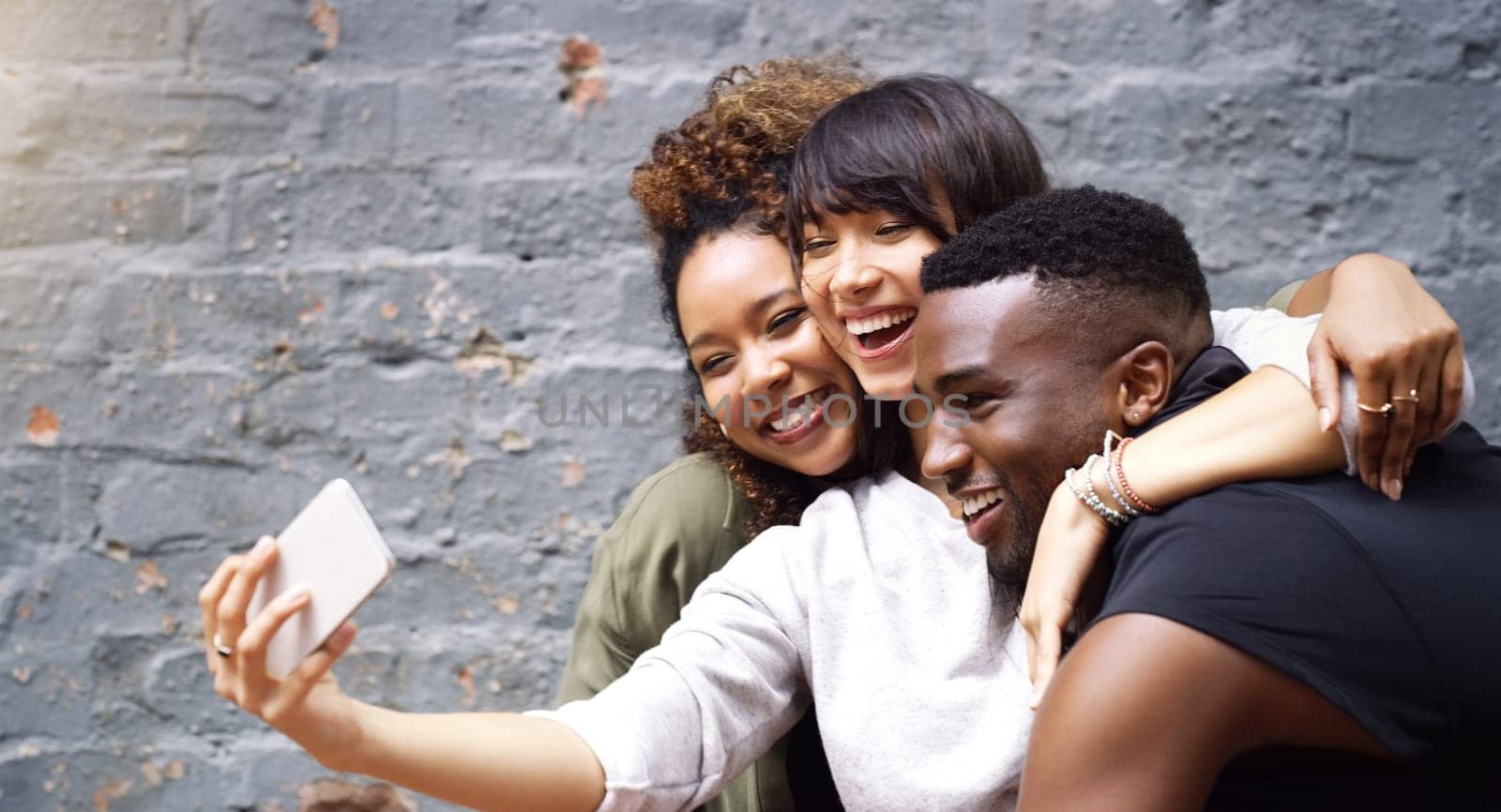 Selfie, social media and smile with friends on brick wall background for profile picture update. App, energy or excitement with happy man and woman group in city for mobile or online photography by YuriArcurs