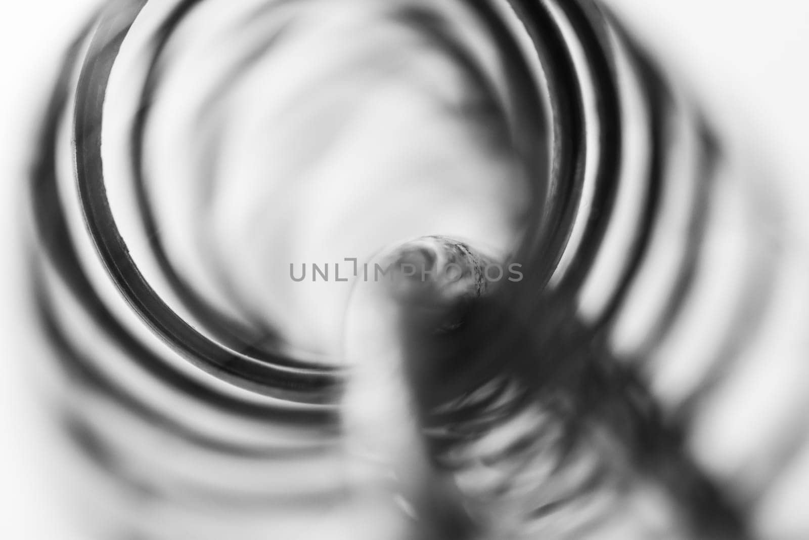 Metal spring coiled, black and white macro shot, soft focus, abstract industrial art